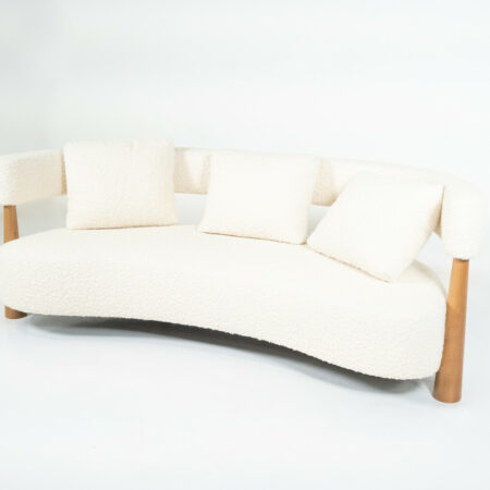 Contemporary Italian bean-shaped sofa with white bouclé upholstery, curved design, and wooden legs